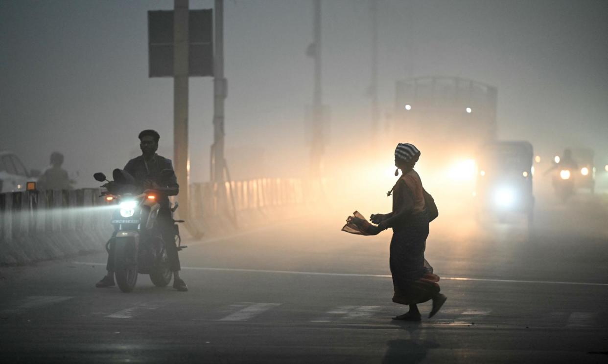 <span>A woman walks across a street engulfed by dense smog in Chennai, India, in the early hours of 14 January 2024.</span><span>Photograph: R Satish Babu/AFP/Getty Images</span>