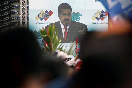 Venezuela's re-elected President Nicolas Maduro is seen on a screen between supporters, after he received a certificate given by the National Electoral Council (CNE), confirming him as winner of Sunday's election, in Caracas, Venezuela May 22, 2018. REUTERS/Carlos Garcia Rawlins
