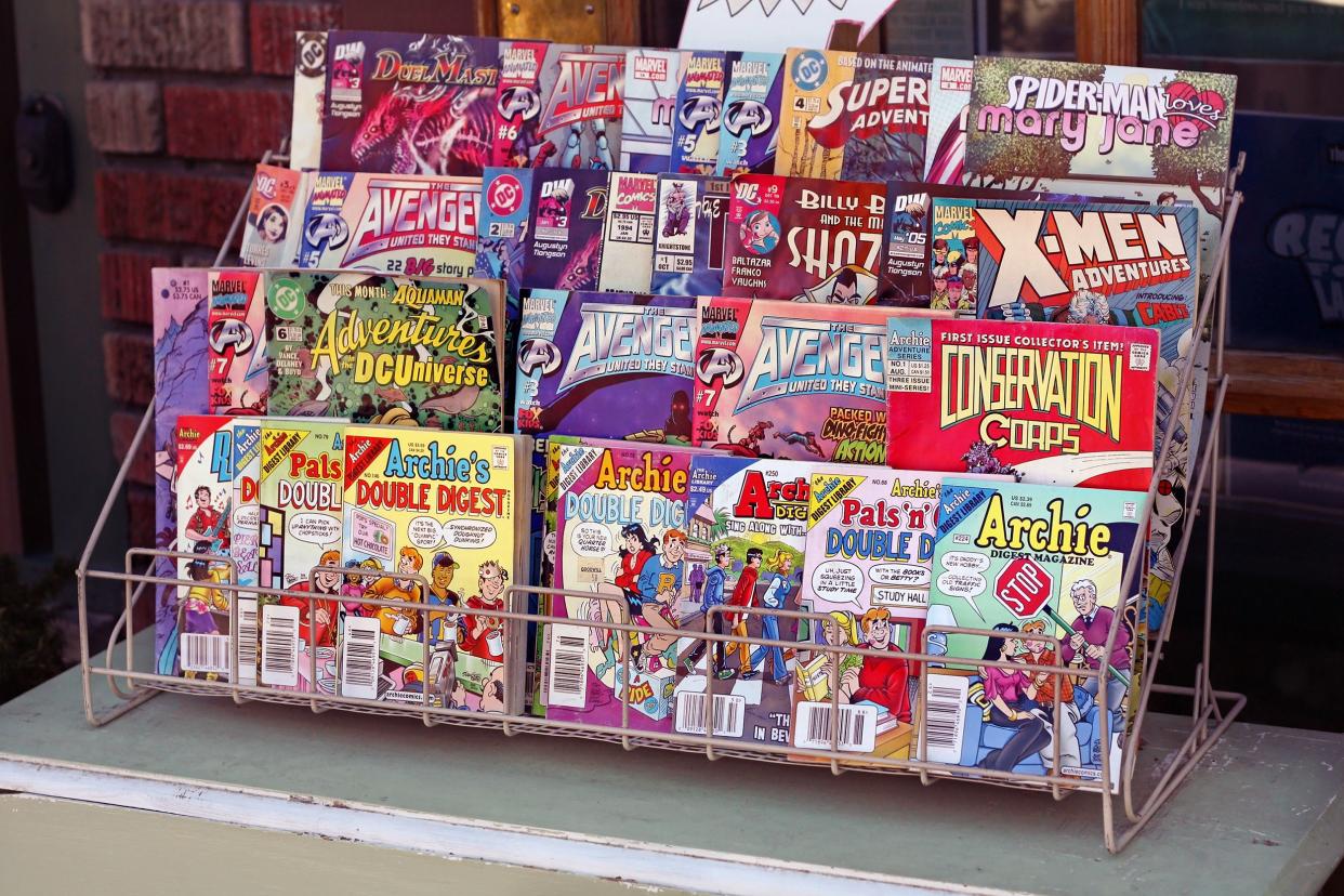 An assortment of popular comic books for sale, shown in a four-row wire display case, outside of a comic book shop in downtown Spokane, Washington