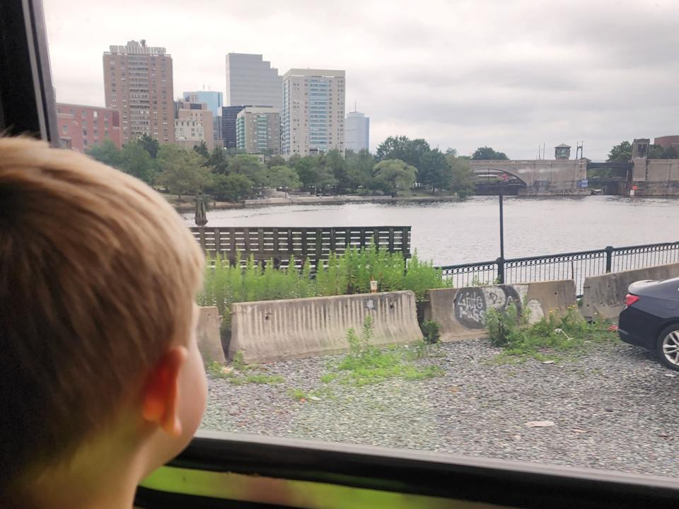 boy looking out of train window at city and water