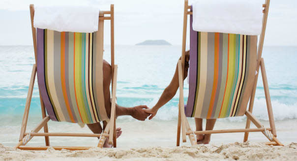 Couple on lounge chairs, holding hands (rear view), St. John, US Virgin Islands, USA