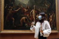 Masked tourist walks by an oil on canvas of 1814 entitled Leonidas at Thermopylae, by Jacques Louis David, at the Louvre Museum in Paris, Thursday, March 5, 2020. With the COVID-19 virus taking firmer hold in Europe, the continent is facing the same complications seen in Asia weeks ago. (AP Photo/Francois Mori)
