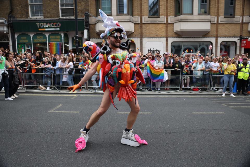 A man covered in inflatable parrots during Pride in London.