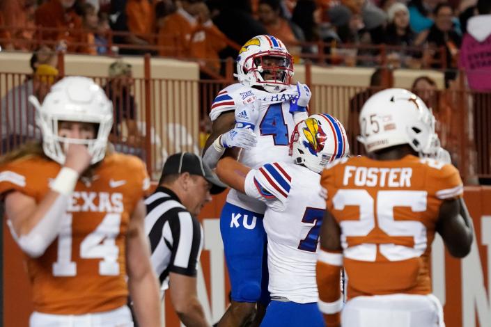 Kansas running back Devin Neal (4) is lifted by offensive lineman Bryce Cabeldue after scoring a touchdown at Texas.