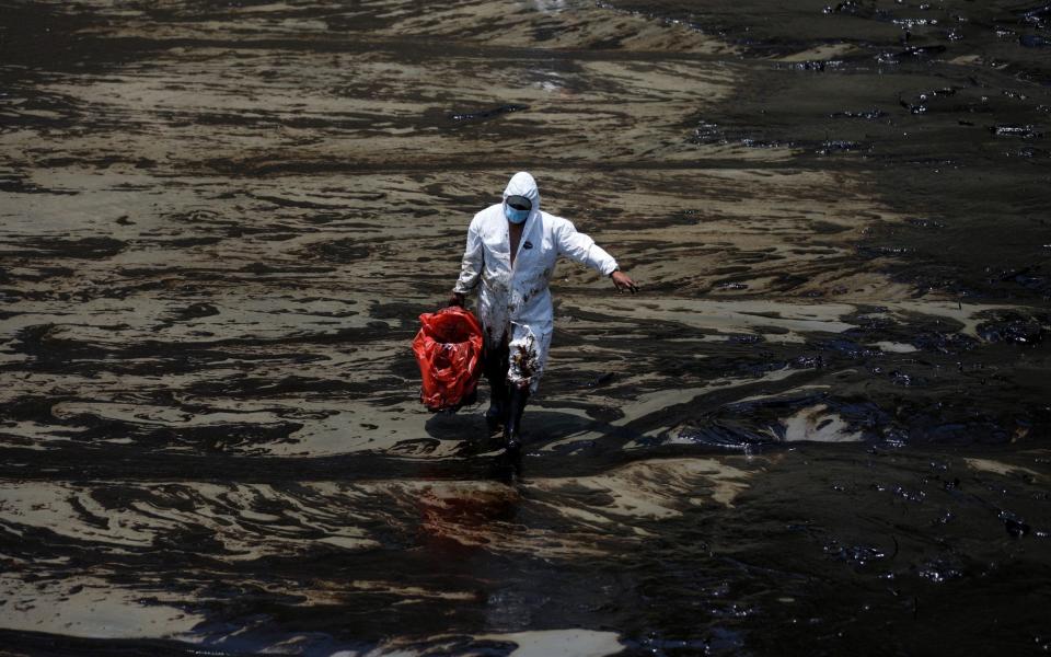 A worker walks following an oil spill caused by abnormal waves, triggered by a massive underwater volcanic eruption half a world away in Tonga - REUTERS