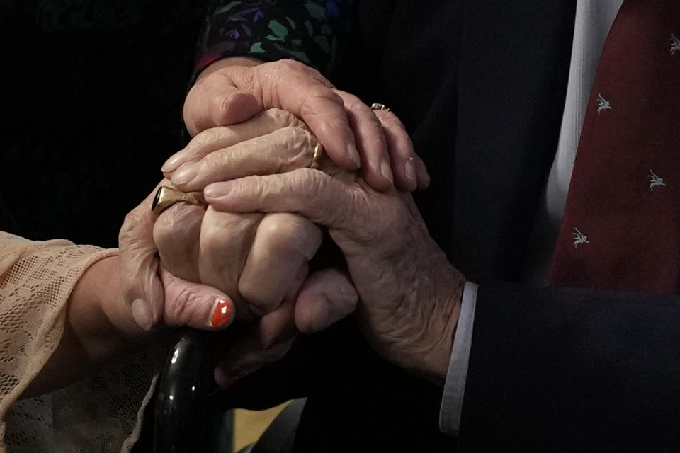 D-Day veteran Bill Gladden holds his daughters and a friend's hand, as he greets friends and family at a surprise 100th birthday party in Haverhill, England, Friday, Jan. 12, 2024. Gladden spoke to the AP on the eve of his 100th birthday, he is a veteran of the British 6th Airborne Armoured Reconnaissance Regiment, part of the British 6th Airborne Division, he landed by glider on the afternoon of D-Day, 6th June 1944 in Normandy, France. (AP Photo/Alastair Grant)