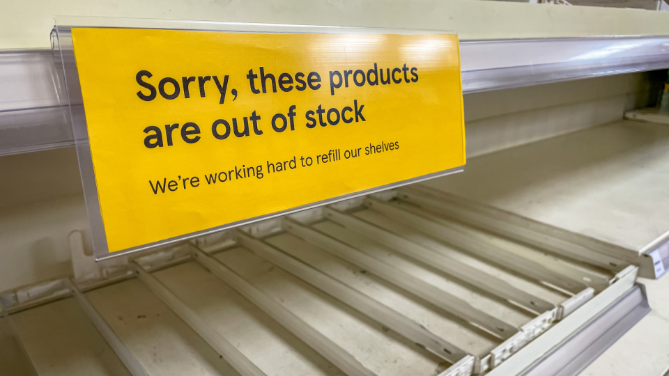 Empty supermarket shelf with sign reading, 'Sorry, these products are out of stock'