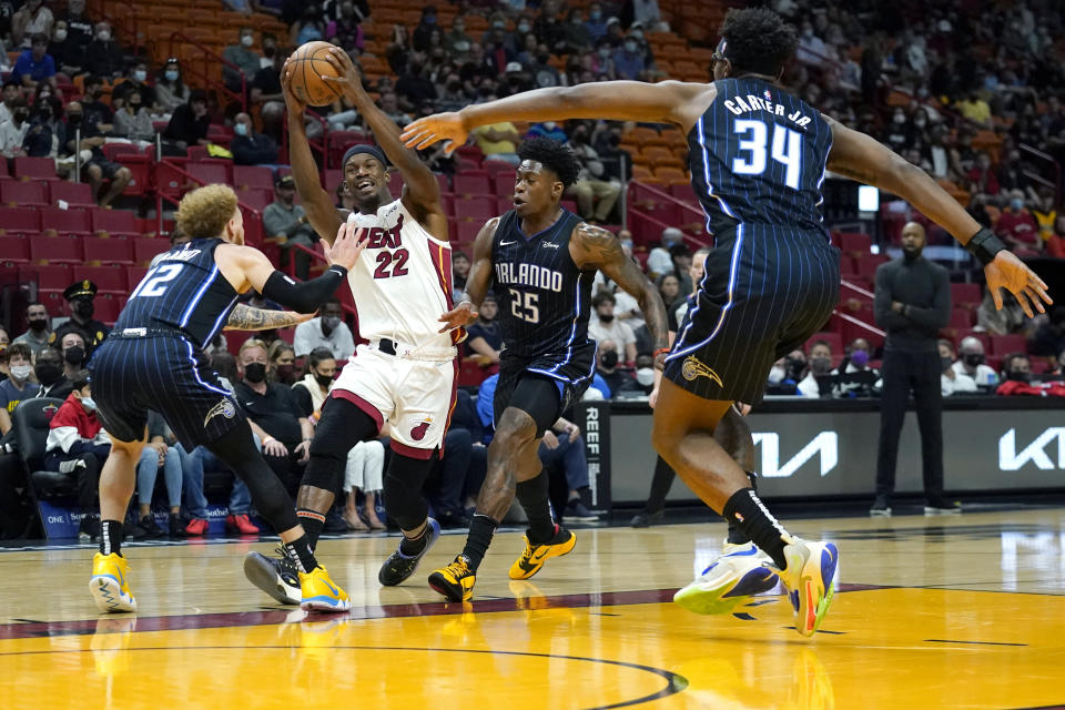 Miami Heat forward Jimmy Butler (22) drives to the basket as Orlando Magic guard Hassani Gravett (12), forward Admiral Schofield (25) and center Wendell Carter Jr. (34) defend during the first half of an NBA basketball game, Sunday, Dec. 26, 2021, in Miami. (AP Photo/Lynne Sladky)