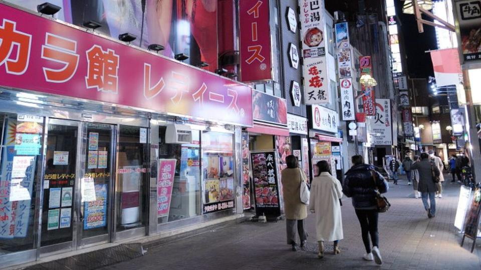 People walk past the entrance of an Karaoke store closed due to the spread of the conoravirus in Tokyo