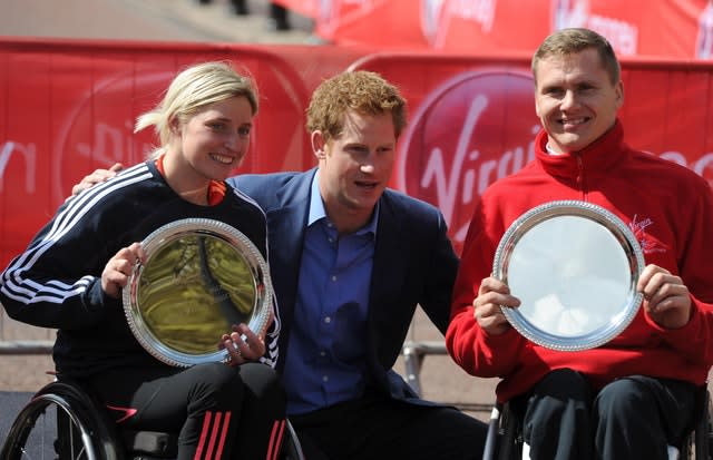 Prince Harry poses with Great Britain’s Shelly Woods and David Weir after their victories in the wheelchair races in 2012