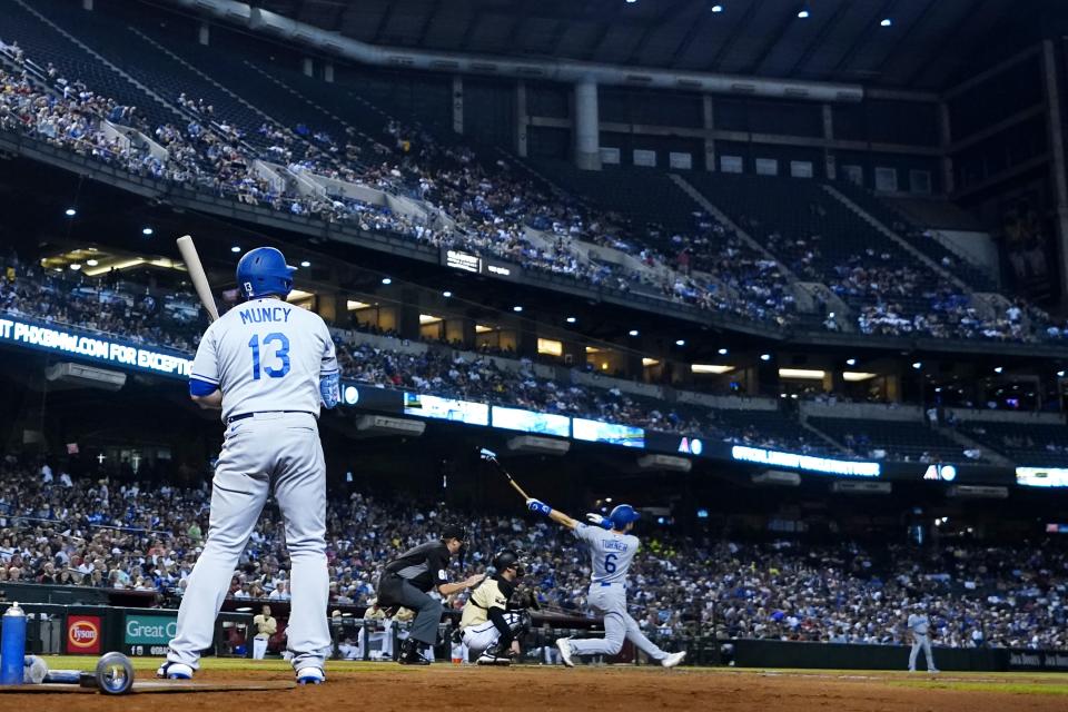 Los Angeles Dodgers' Trea Turner (6) connects for a home run as Dodgers' Max Muncy (13), umpire Chad Whitson, second from left, and Arizona Diamondbacks catcher Carson Kelly look on during the sixth inning of a baseball game Saturday, Sept. 25, 2021, in Phoenix. (AP Photo/Ross D. Franklin)