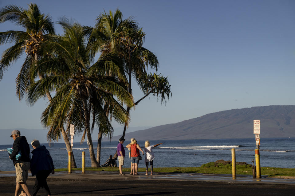 Beachgoers look at the ocean on Friday, Feb. 23, 2024, in Lahaina, Hawaii. A deadly wildfire burned more than 2,000 buildings in the Hawaiian town of Lahaina on Maui last August and left behind piles of toxic debris. Research now underway could provide the community a sense of how the ocean that shapes their lives is weathering the disaster. It may also inform travelers to Maui's famed shores whether they should enter the water. (AP Photo/Mengshin Lin)