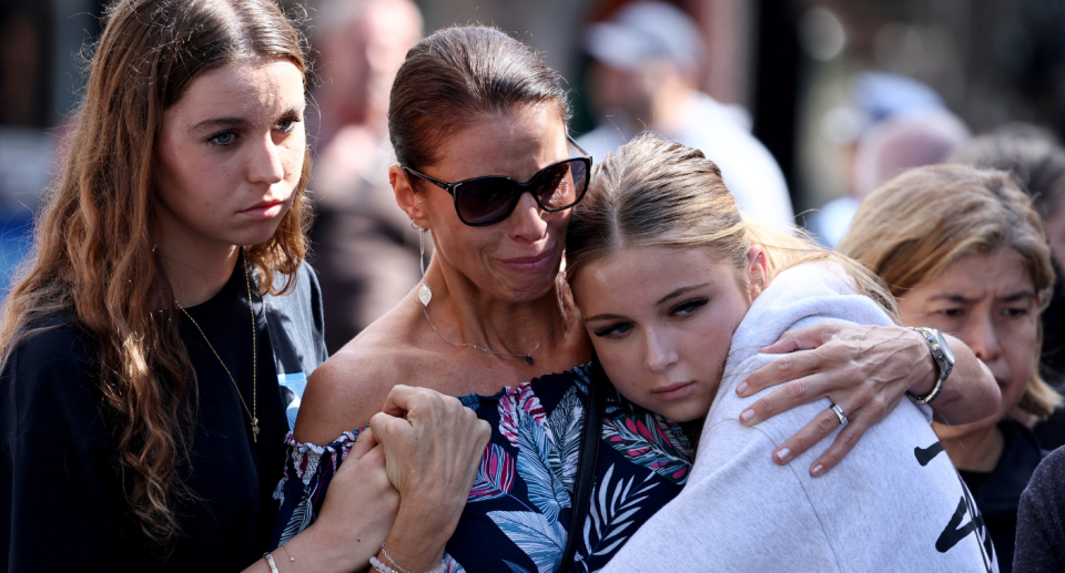 A woman holding two teenage girls.