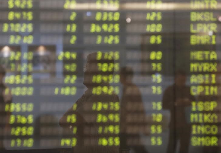 A man stands near an electronic board showing the stock market index at the Bank Mandiri Sekuritas trading floor in Jakarta November 25, 2015. REUTERS/Beawiharta