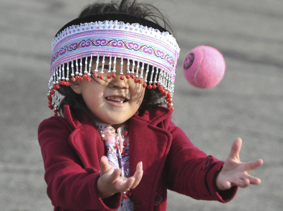 Four-year-old Vania Yang peers through her beaded hat to play the traditional game of Pov Pob during the first day of the Hmong New Year celebration at the Fresno Fairgrounds, Thursday Dec. 26, 2019. (John Walker/The Fresno Bee via AP)
