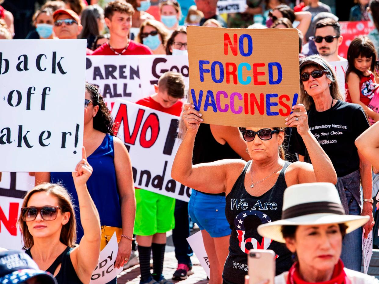 <p>A woman with a QAnon shirt protesting a mandate from the Massachusetts Governor requiring all children, aged K-12, to receive a flu vaccine</p> (AFP via Getty Images)