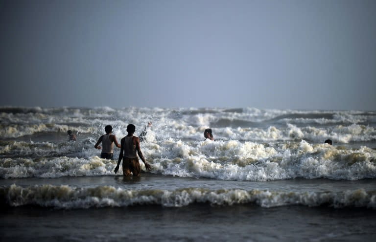 Pakistanis wade in waters off the coast of Clifton beach on the Arabian Sea in Karachi on June 8, 2011