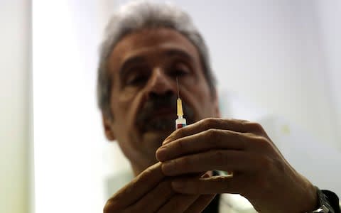 An Italian doctor checks a syringe before vaccinating a child in Rome - Credit: Alessandra Tarantino/AP