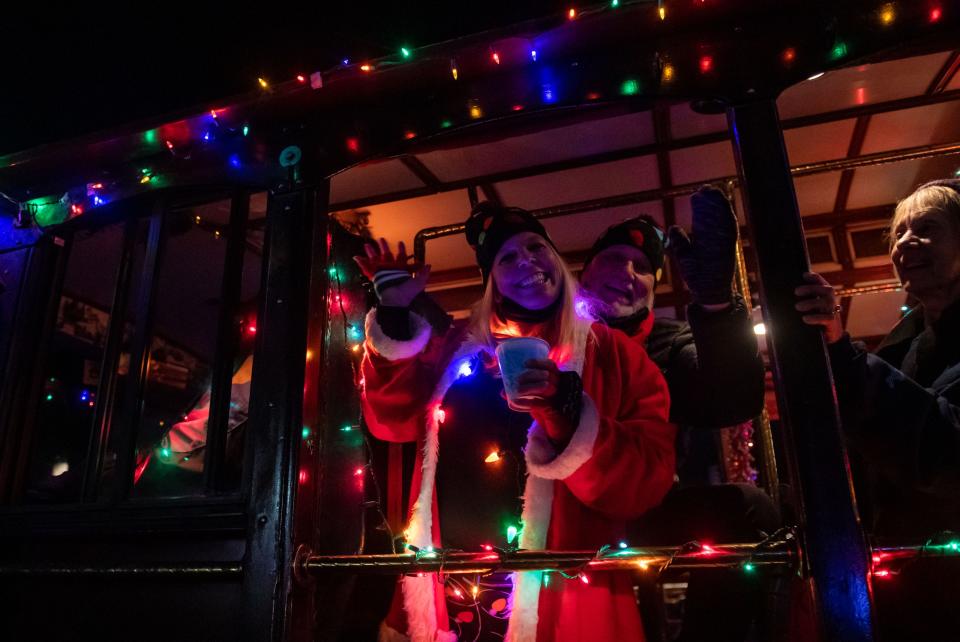 People on a trolley wave and smile as they pass dozens of people during the annual Holiday Parade of Lights in Pacific Grove, Calif., on Thursday Dec. 2, 2021. 