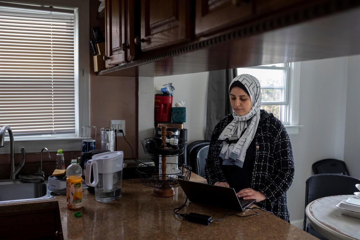 Sara Shannan, 27, a mother and University of Detroit Mercy student from Gaza, uses her computer to try to connect with her family as she stands inside her kitchen home in Dearborn on Wednesday, Feb. 21, 2024.