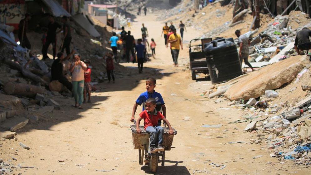 A young boy wheels a wheelbarrow through Gaza