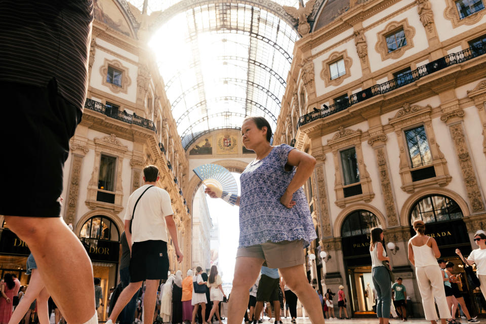 Una mujer se abanica mientras camina por el centro comercial Galleria Vittorio Emanuele en Milán, Italia, el lunes 17 de julio de 2023. (Camilla Ferrari/The New York Times)