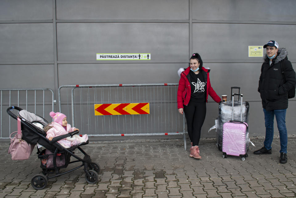 Ana-Maria Hasu and her partner Andrei Otelea, who live in the U.K with their baby, stand after arriving at the Sibiu International airport in central Romania, Tuesday, Dec. 28, 2021, the first time the couple, who are both unvaccinated against COVID-19, flew home since the pandemic started. As the fast-spreading coronavirus variant omicron rages through Western Europe, officials and experts in low-vaccinated Eastern Europe view it as a forewarning for what much of the region anticipates to be an imminent, post-holiday virus surge.(AP Photo/Stephen McGrath)