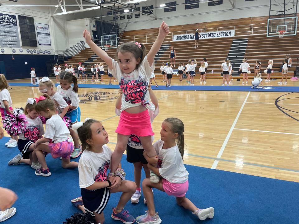 Ruby Rose, 5, practices her flying skills with the help of her friends Lillian, 5, Mackenzie, 5, and Olivia, 5, at the cheerleading camp held at Farragut High School Wednesday, June 15, 2022.