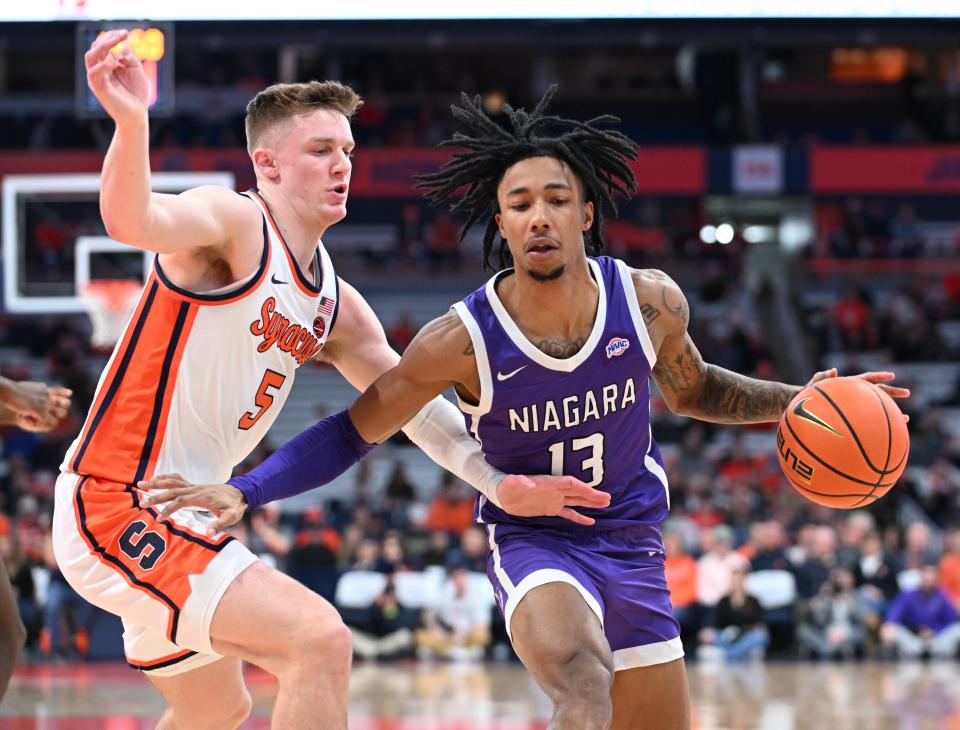 Dec 21, 2023; Syracuse, New York, USA; Niagara Purple Eagles guard Dre Bullock (13) drives the ball as Syracuse Orange guard Justin Taylor (5) defends in the first half at the JMA Wireless Dome. Mandatory Credit: Mark Konezny-USA TODAY Sports