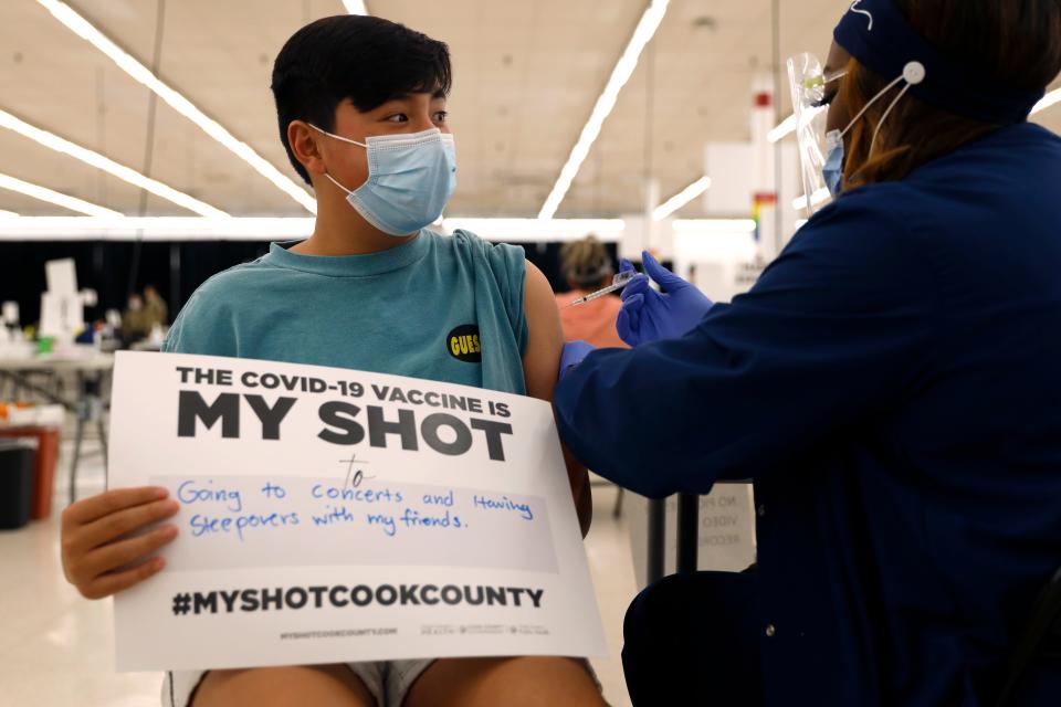 Lucas Kittikamron-Mora, 13, holds a sign in support of COVID-19 vaccinations as he receives his first Pfizer shot on May 13 in Des Plaines, Illinois.