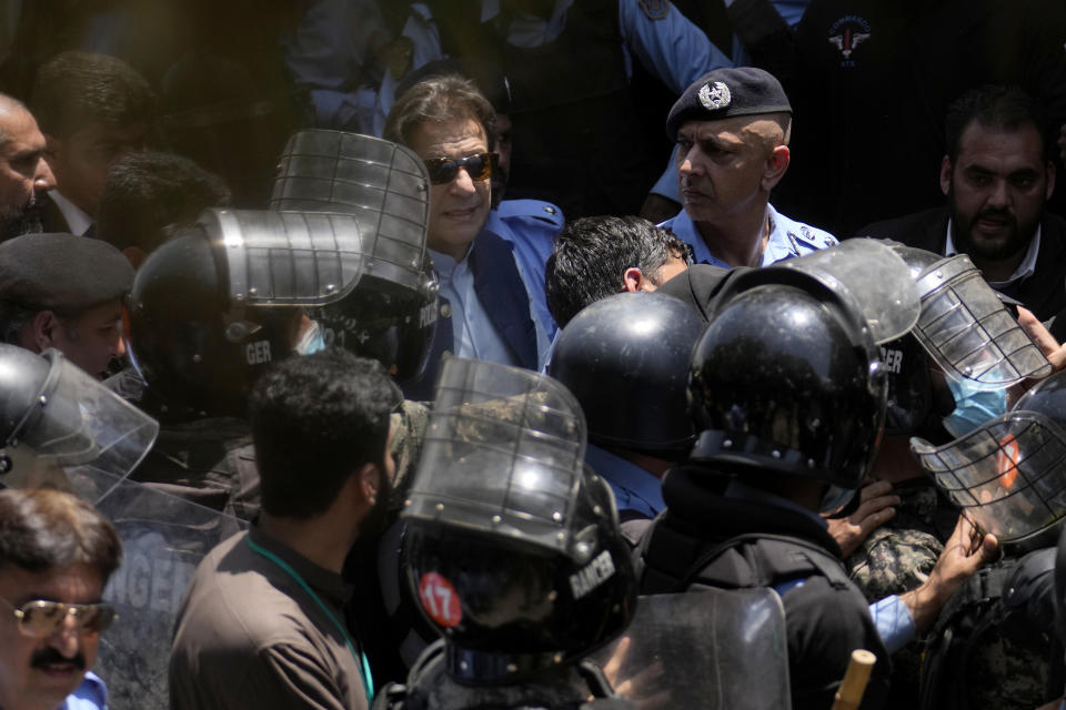 Pakistan's former Prime Minister Imran Khan, top center, is escorted by police officers as he arrives to appear in a court, in Islamabad, Pakistan, Friday, May 12, 2023. A high court in Islamabad has granted Khan a two-week reprieve from arrest in a graft case and granted him bail on the charge. (AP Photo/Anjum Naveed)