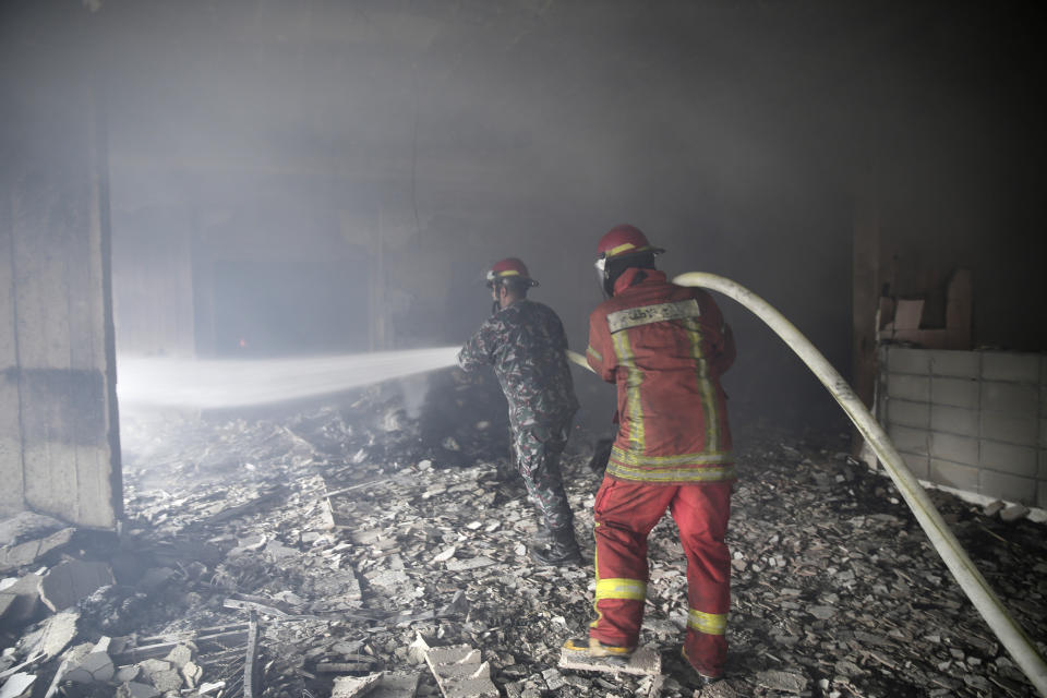 Lebanese firemen extinguish a fire inside a building that was burned in a wildfire overnight, in the town of Damour just over 15km (9 miles) south of Beirut, Lebanon, Tuesday, Oct. 15, 2019. Strong fires spread in different parts of Lebanon forcing some residents to flee their homes in the middle of the night as the flames reached residential areas in villages south of Beirut. (AP Photo/Hassan Ammar)