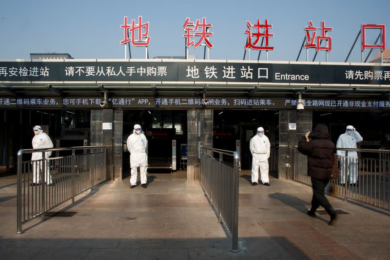 Trabajadores toman la temperatura corporal de los pasajeros antes de ingresar a la estación de metro que lleva a una estación de trenes de Pekín.