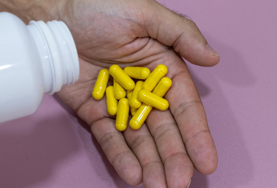 Hands holding yellow capsules, curcuma, berberine. (Getty Images)