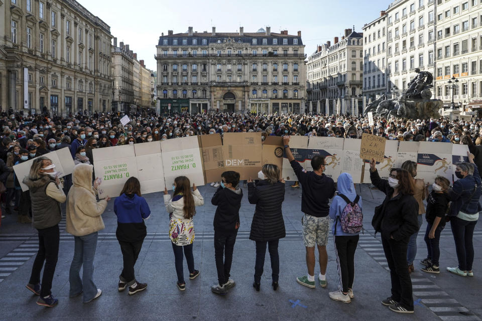 Varias personas sostienen un conjunto de pancartas que leen "No toquen a mi maestro", frente a una multitud de manifestantes en Lyon, Francia, el domingo 18 de octubre de 2020. (AP Foto/Laurent Cipriani)