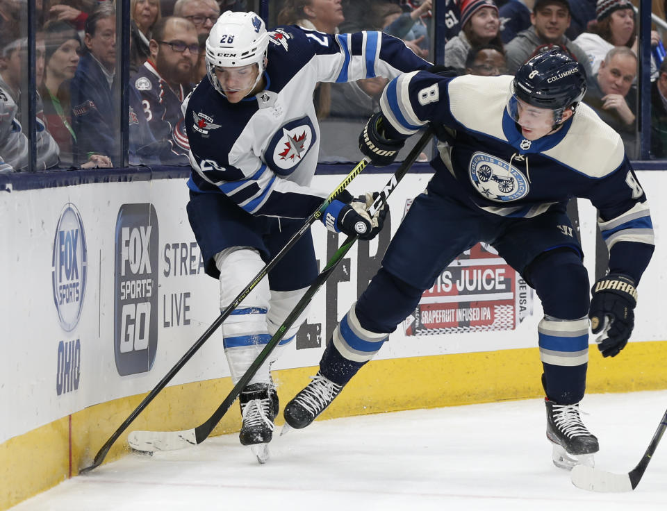 Winnipeg Jets' Blake Wheeler, left, and Columbus Blue Jackets' Zach Werenski fight for a loose puck during the first period of an NHL hockey game Wednesday, Jan. 22, 2020, in Columbus, Ohio. (AP Photo/Jay LaPrete)