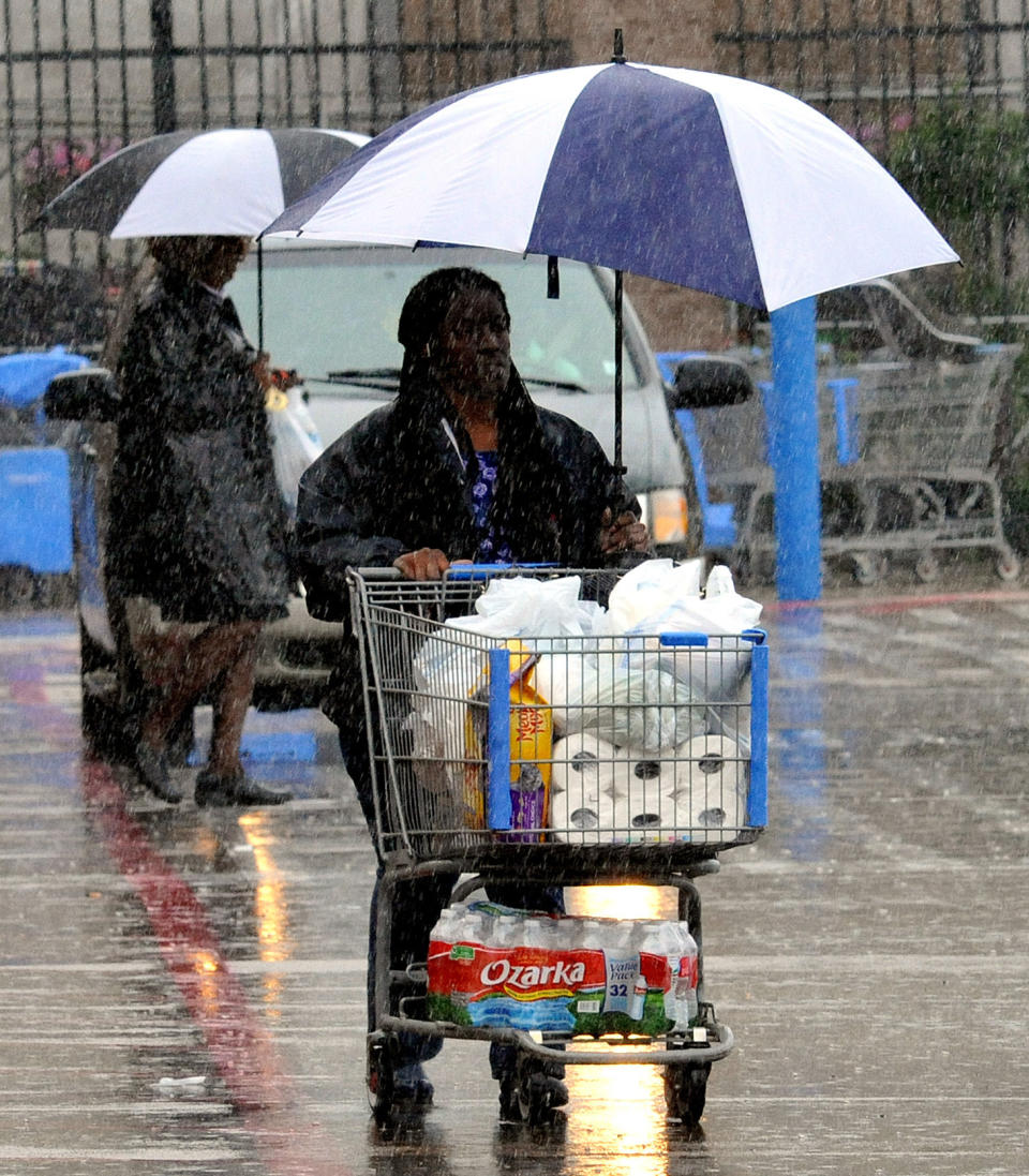 Shoppers attempt to keep dry during heavy rains on Sunday, April 6, 2014 in Ridgeland, Miss. On Sunday, street flooding plagued Jackson. Flood advisories for much of the state continued into Monday. (AP Photo/The Clarion-Ledger, Rick Guy ) NO SALES