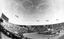 FILE - In this Oct. 10, 1964, file photo, vapor trails from Japanese Self-Defense Force jets form the Olympic emblem of the five rings above the National Stadium in Tokyo for the official opening of the XVIII Olympiad, first even held in Asia. Every Japanese of a certain age has memories of the 1964 Tokyo Olympics. Even younger Japanese have connections through parents or aunts and uncles who saved old photos, faded certificates, or recall getting a television for the first time to watch the Games. (AP Photo, File)