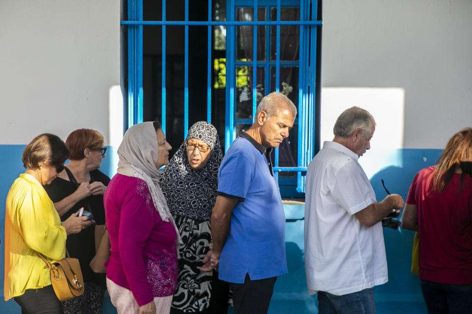 Voters queue outside a polling station during a parliamentary election in La Marsa, outside Tunis, Tunisia, Sunday, Oct. 6, 2019. Tunisians were electing a new parliament Sunday amid a tumultuous political season, with a moderate Islamist party and a jailed tycoon's populist movement vying to come out on top of a crowded field. (AP Photo/Riadh Dridi)