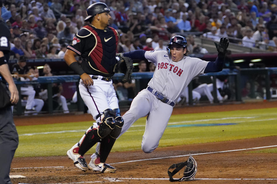 Boston Red Sox Triston Casas, right, scores on a sacrifice bunt by Reese McGuire during the fourth inning of a baseball game as Arizona Diamondbacks catcher Gabriel Moreno looks on, Saturday, May 27, 2023, in Phoenix. (AP Photo/Matt York)