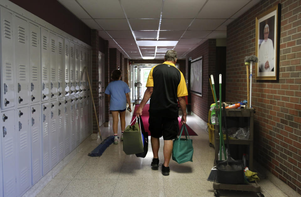 Cesa Pusateri, 12, and her grandfather, Timothy Waxenfelter, principal of Quigley Catholic High School, leave with his collection of speech and debate books after the recent closure of the school in Baden, Pa., Monday, June 8, 2020. According to the National Catholic Educational Association, at least 100 schools have announced in recent weeks that they won't reopen this fall. (AP Photo/Jessie Wardarski)