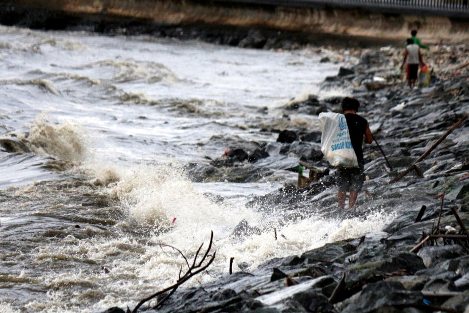 <p>People collect garbage along the Manila Bay sea wall in Manila City, Philippines, on July 7, 2014.&nbsp;</p>