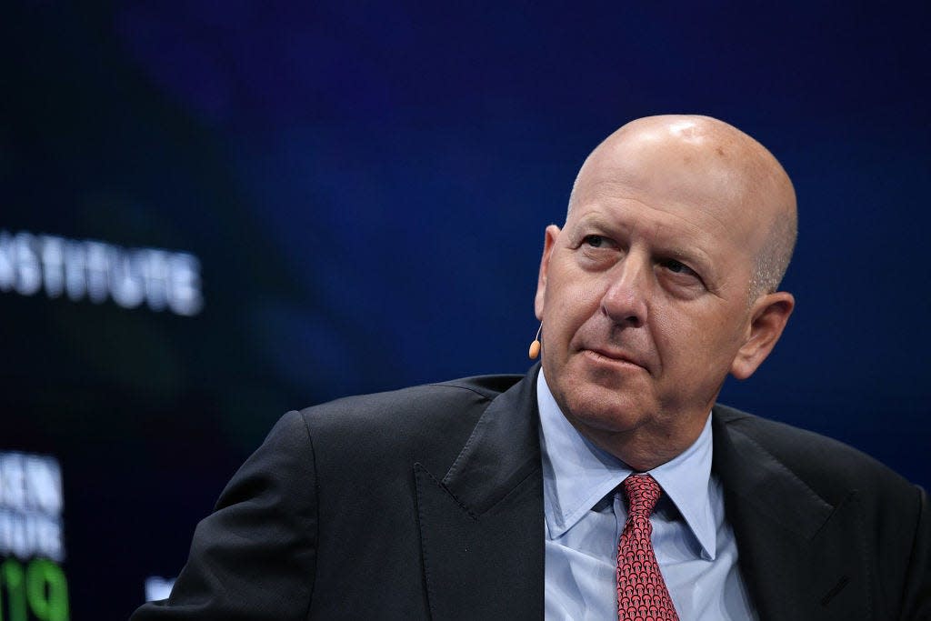 David Solomon, the CEO of Goldman Sachs, wears a dark suit and a red tie while speaking at a conference.