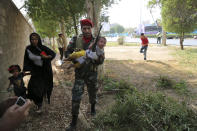 In this photo provided by Mehr News Agency, an Iranian army member carries away a child from a shooting scene during a military parade marking the 38th anniversary of Iraq's 1980 invasion of Iran, in the southwestern city of Ahvaz, Iran, Saturday, Sept. 22, 2018. Gunmen attacked the military parade, killing at least eight members of the elite Revolutionary Guard and wounding 20 others, state media said. (AP Photo/Mehr News Agency, Mehdi Pedramkhoo)