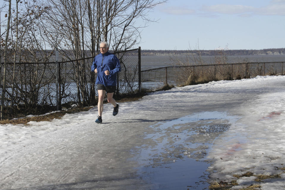 This April 3, 2019, photo shows a man wearing shorts running on the coastal trail in Anchorage, Alaska. Much of Anchorage's snow disappeared as Alaska experienced unseasonably warm weather in March. (AP Photo/Mark Thiessen)