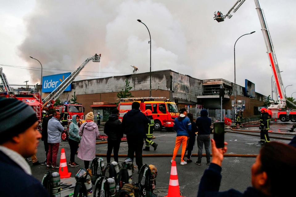 Firefighters extinguish the fire at a Santiago supermarket in which three people were killed (AFP via Getty Images)