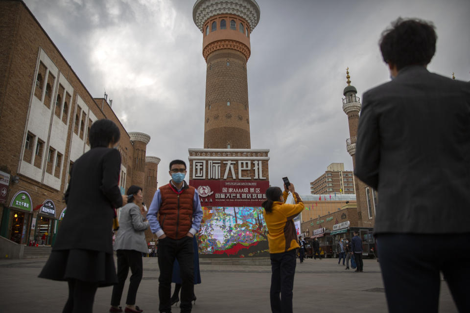 FILE - Tourists take photos near a tower at the International Grand Bazaar in Urumqi in western China's Xinjiang Uyghur Autonomous Region, as seen during a government organized trip for foreign journalists on April 21, 2021. A prominent Uyghur scholar specializing in the study of her people's folklore and traditions has been sentenced to life in prison, according to a U.S.-based foundation that works on human rights cases in China. Rahile Dawut was convicted on charges of endangering state security in December 2018 in a secret trial, the San Francisco-based Dui Hua Foundation said in a statement Thursday, Sept. 21, 2023. (AP Photo/Mark Schiefelbein)