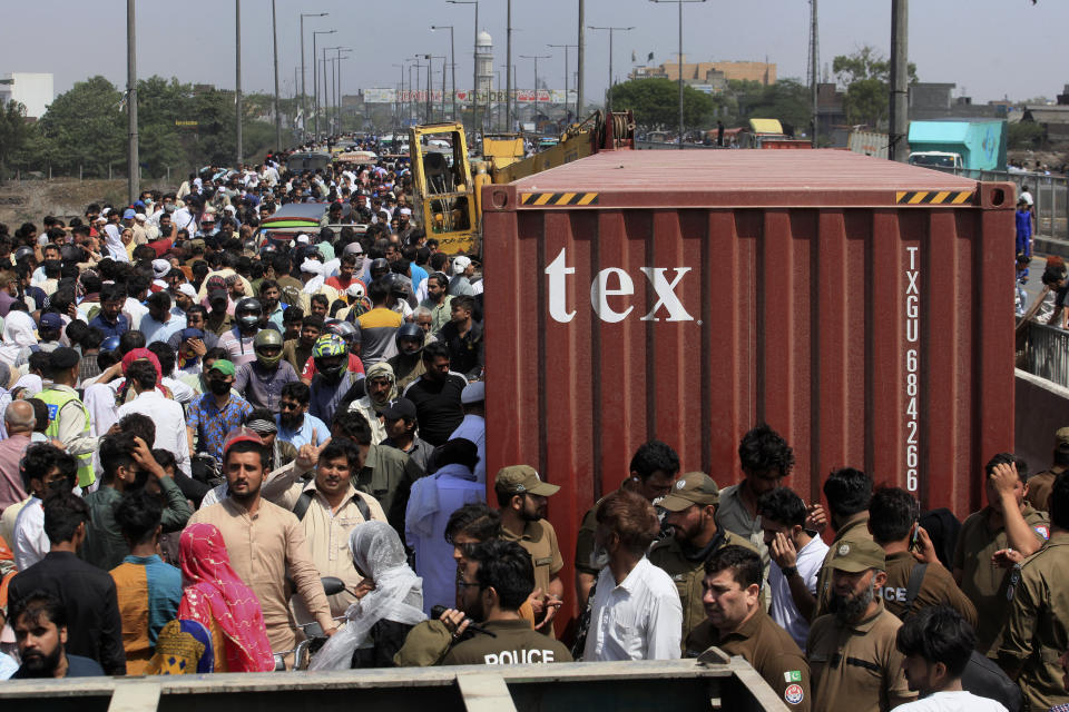 People cross a bridge on Ravi River which is closed for traffic due to shipping containers placed by authorities in an attempt to foil a planned protest of Pakistan's main opposition party, in Lahore, Pakistan, Tuesday, May 24, 2022. Pakistan's key opposition party led by recently ousted Prime Minister Imran Khan accused police of detaining hundreds of its supporters in raids that started early Tuesday. (AP Photo/K.M. Chaudary)