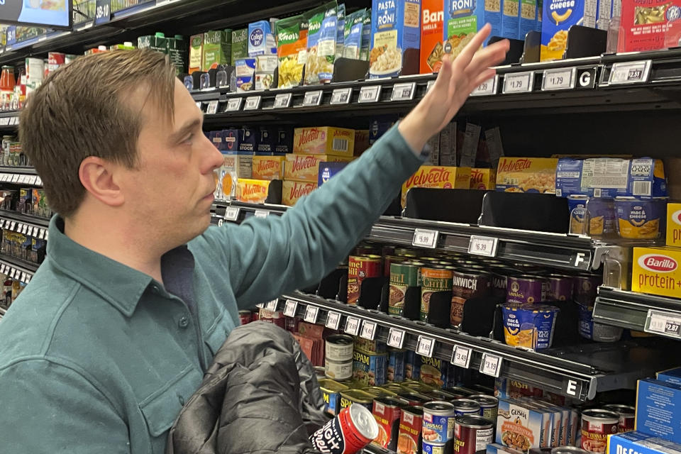 Stuart Dryden reaches for an item at a grocery store on Wednesday, Feb. 21, 2024, in Arlington, Va. Dryden is aware of big price disparities between branded products and their store-label competitors, which he now favors. (Credit: Chris Rugaber, AP Photo via Getty Images)