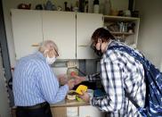 Petr Brandejsky, a 90-year-old Holocaust survivor, is helped by a volunteer to prepare his lunch at his apartment in Prague